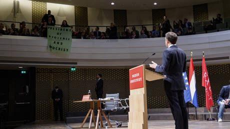 Students deploy a protest banner during French President Emmanuel Macron's speech to the Nexus Institute in The Hague on April 11, 2023.