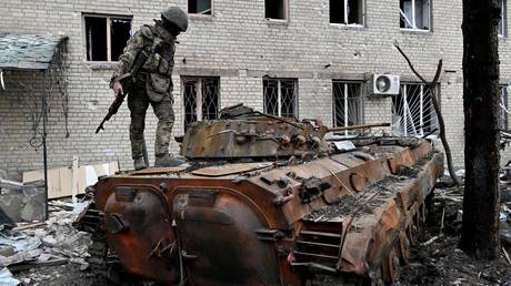 FILE PHOTO: Servicemen of Russia's private military company Wagner Group inspect a destroyed infantry fighting vehicle in Artyomovsk, Donetsk People's Republic