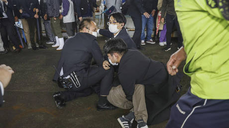 A man, on the ground, who threw what appeared to be a smoke bomb, is caught at a port in Wakayama, western Japan, April 15, 2023
