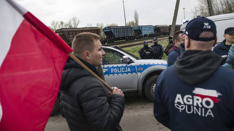 Protesting farmers watch a train that carries Ukrainian grain at the broad-gauge railway line crossing in Hrubieszow, Poland on April 12, 2023.