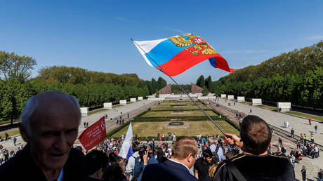 FILE PHOTO. A man waves a Russian flag at the Soviet memorial in Treptower Park in Berlin, Germany.