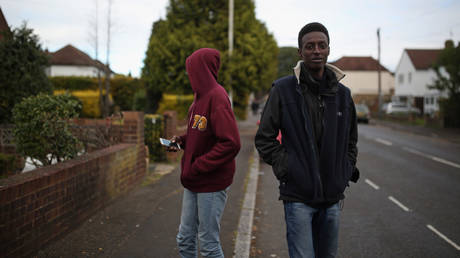 FILE PHOTO. Two asylum seekers from Sudan walk down the road in Longford, England.