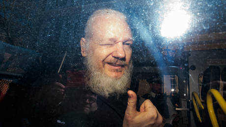 Julian Assange gestures to the media from a police vehicle on his arrival at Westminster Magistrates court on April 11, 2019 in London, England