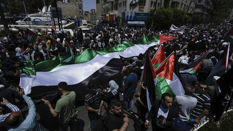 Palestinians march with their national flag in a rally marking the 75th anniversary of what they call the "Nakba," in the West Bank city of Ramallah, May 15, 2023.