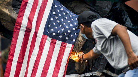 FILE PHOTO: A demonstrator sets fire to a United States flag hanging on a paper statue, symbolizing that, US backed militarism during the massacre of students in 1975, El Salvador, 2021.