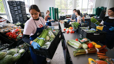 15 May 2023, Schleswig-Holstein, Lübeck: Volunteers unpack and sort food at a distribution point to then distribute it to those in need.