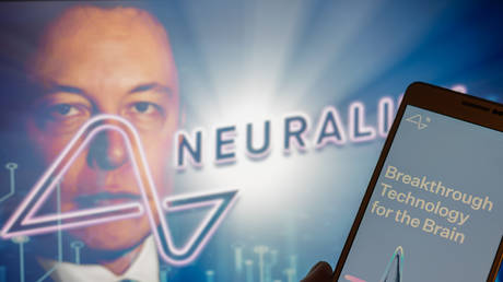 Neuralink logo displayed on mobil with founder Elon Musk seen on screen in the background