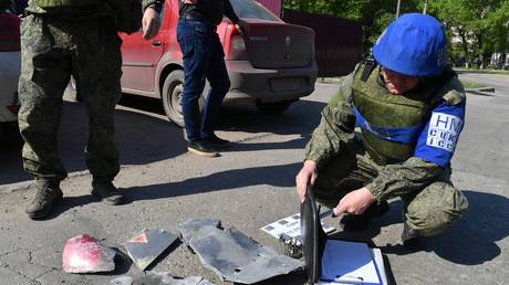 A member of the Joint Center for Control and Coordination of issues related to Ukraine's war crimes (JCCC) is seen near fragments of a rocket on a street in Luhansk.