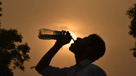 A man drinks water from the water bottle during a hot weather, as the heat wave conditions prevailed in Northern India