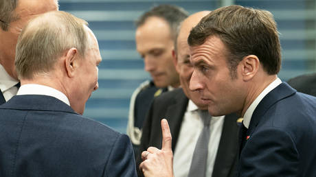 French President Emmanuel Macron speaks with Russian President Vladimir Putin before a meeting at the Chancellery on January 19, 2020 in Berlin, Germany