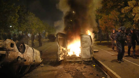 Police forces walk past burning cars in Nanterre, outside Paris, June 29, 2023.