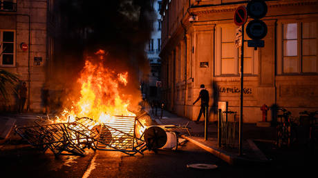 A bonfire near a graffiti reading "The police kills" during clashes with police in the streets of Lyon, south-eastern France, on June 30, 2023.