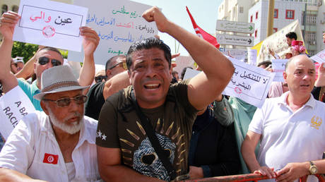 People lift placards as they shout slogans during a demonstration against the presence of illegal sub-Saharan migrants, in Sfax on June 25, 2023.