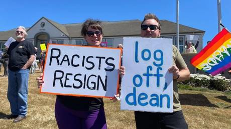 Protesters hold signs following the resignation of Newport Mayor Dean Sawyer, at city hall in Newport, Oregon, July 10, 2023.