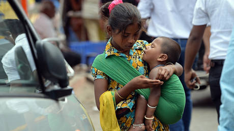 An Indian youth carrying a toddler counts money collected by begging from commuters at a busy traffic intersection on the eve of World Day Against Child Labour in Mumbai on June 11, 2014.