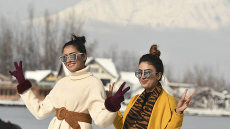 Indian tourists pose on the shores of Dal lake after a heavy snowfall in Srinagar on January 6, 2021. TAUSEEF MUSTAFA / AFP