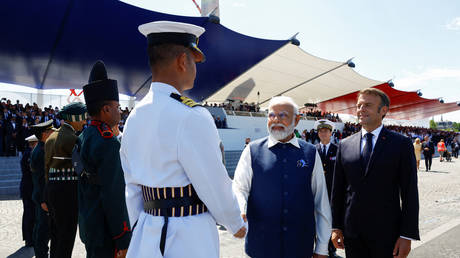 India's Prime Minister Narendra Modi (C) and French President Emmanuel Macron (R) review troops during the Bastille Day military parade on the Champs-Elysees avenue in Paris on July 14, 2023.