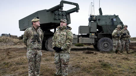 Servicemen stand in front of the HIMARS rocket system during the Dynamic Front military exercise led by the US in Denmark on March 30, 2023.