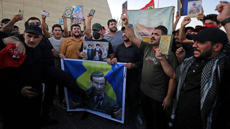 Iraqi demonstrators hold a poster depicting Swedish Prime Minister Ulf Kristersson with a large X mark drawn over it during a protest in Baghdad.