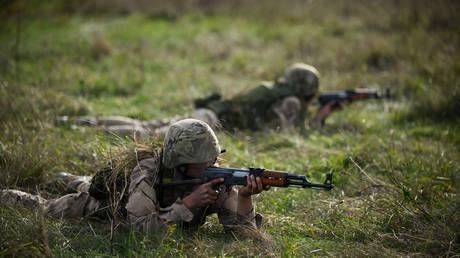 A Ukrainian recruit aims an unloaded AK-47 rifle during a combat training course with the UK armed forces in southern England on October 11, 2022.