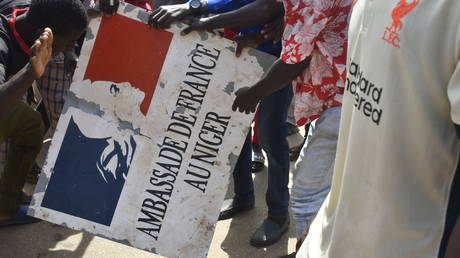 Protesters hold a sign taken from the French Embassy in Niamey during a demonstration that followed a rally in support of Niger's junta in Niamey on July 30, 2023.
