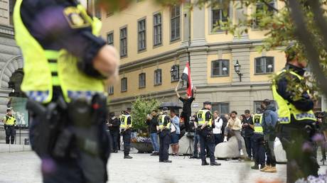 Policemen stand next to demonstrators, one holding an Iraqi flag, at Mynttorget square in Stockholm, Sweden, July 31, 2023