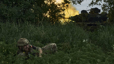 A Ukrainian soldier lies on the ground as a tank fires toward Russian positions near Artyomovsk, Russia, June 17, 2023