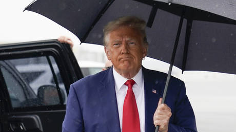 Former President Donald Trump walks over to speak with reporters before he boards his plane at Ronald Reagan Washington National Airport, August 3, 2023