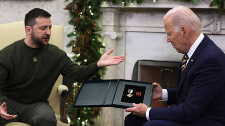 President of Ukraine Vladimir Zelensky presents a medal from a Ukrainian soldier to U.S. President Joe Biden during a meeting in the Oval Office of the White House on December 21, 2022 in Washington, DC