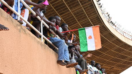 A man waves a Nigerien flag as supporters cheer from the stands while artists perform during a concert in support to Niger's National Council for the Safeguard of the Homeland (CNSP)  on August 13, 2023.