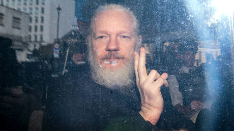 Julian Assange gestures to the media from a police vehicle on his arrival at Westminster Magistrates court on April 11, 2019 in London, England