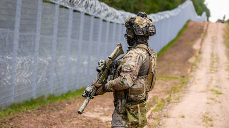 A member of the State Border Guard patrols along the fence at the Latvia/Belarus border near Krivanda, on August 8, 2023, during a vist by the President of Latvia.