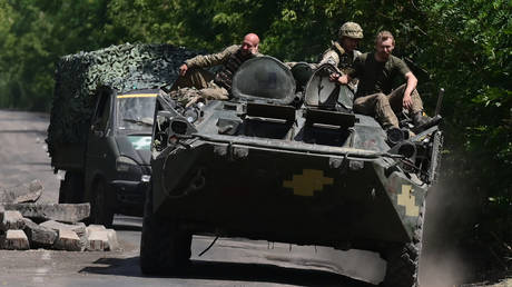 FILE PHOTO: Ukrainian soldiers sit on a armoured vehicle as they drive on a road.