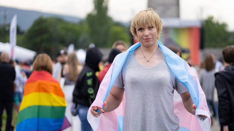 FILE PHOTO: Transgender woman standing and wearing a flag at gay pride event.