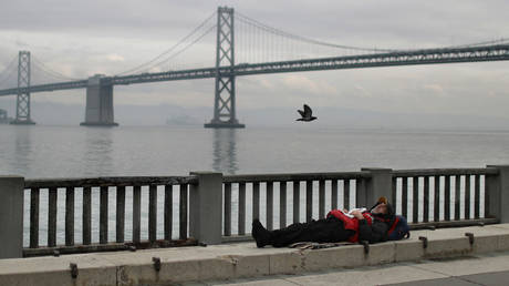  A homeless man sleeps on the sidewalk near the San Francisco Oakland Bay Bridge