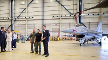 Ukraine's President Vladimir Zelensky (2nd-R) and Dutch PM Mark Rutte (R) standing next to a F-16 fighter jet at the Eindhoven airbase.