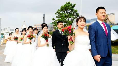 Couples attend a collective wedding at Love Bay, Golden Beach Beer City in Qingdao, Shandong province, China, August 22, 2023.