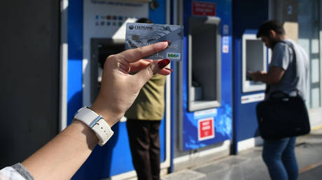А woman holds her MIR credit card of SberBank while standing near an ATM in Istanbul, Turkey.