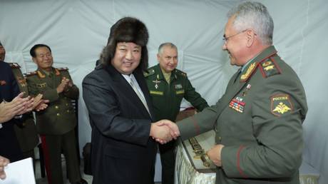 North Korean leader Kim Jong-un wearing Russian ushanka hat, shakes hands with Russia’s Defense Minister Sergey Shoigu.