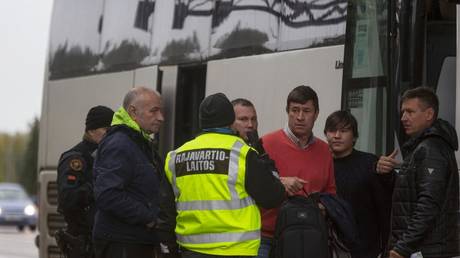 A Finnish border guard speaks with Russian men at the Vaalimaa border crossing between Finland and the Russian Federation, September 30, 2022