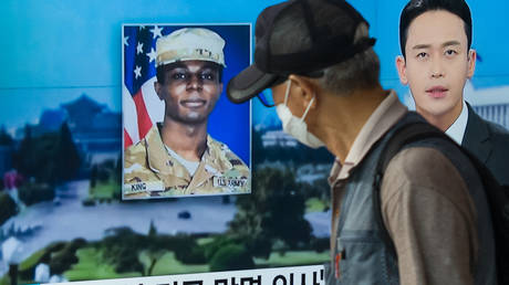 A man walks past a television showing a news broadcast featuring a photo of US soldier Travis King, who ran across the border into North Korea on July 18, 2023.