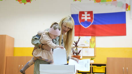 A girl casts a vote for her mother at a polling station during an early parliamentary election in Bratislava, Slovakia, September 30, 2023