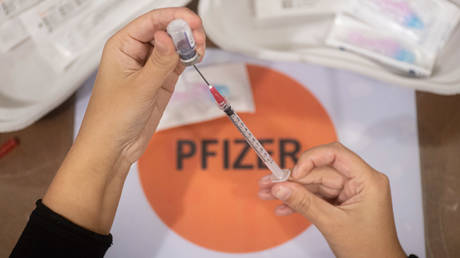 A female GGD healthcare worker prepares the Pfizer - BioNTech Covid-19 vaccines drawing them from the vial glass bottle to the syringes in the special area at the mega vaccination center in Eindhoven on January 7, 2022