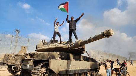 Palestinians stand atop of a destroyed Israeli tank on October 07, 2023. (Photo by via Getty Images)