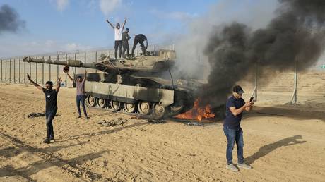 FILE  PHOTO: Palestinians celebrate by a destroyed Israeli tank near the Gaza border wall