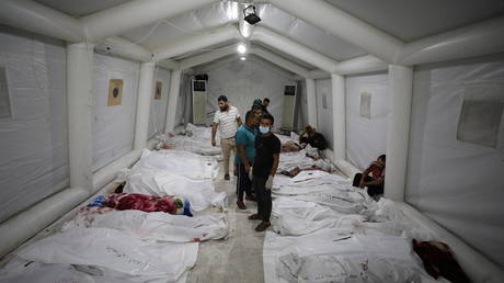 People stand over bodies of Palestinians killed in Israeli airstrikes on the Ahli Arab hospital in central Gaza on October 17, 2023 © Dawood Nemer / AFP