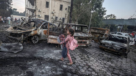 A girl tries to collect usable belongings amid wreckage of vehicles after Al-Ahli Baptist Hospital was hit in Gaza City, Gaza on October 18, 2023.