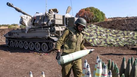 An Israeli soldier moves a 155mm artillery shell near a self-propelled howitzer  in the upper Galilee region of northern Israel, October 18, 2023