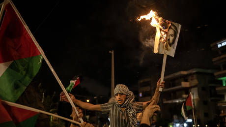 A protester holds a burning picture of European Commission President Ursula von der Leyen outside the Israeli Embassy in Athens on October 18, 2023