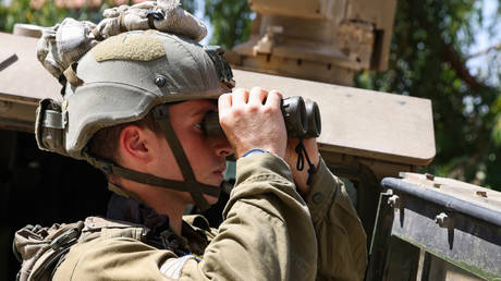 An Israeli soldier uses a binoculars during a patrol in the town of Ghajar in the Golan Heights on July 6, 2023.